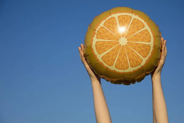 Літня цитрусова фруктова куля тримається в повітрі проти яскравого блакитного — стокове фото