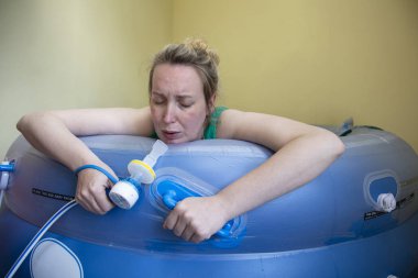 A pregnant woman using gas and air in a birth pool during a natural home birth clipart
