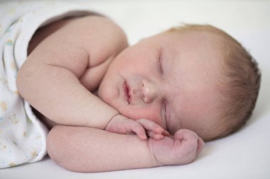 Kollarında uyuyan şirin bir bebeğin yakın çekimi.