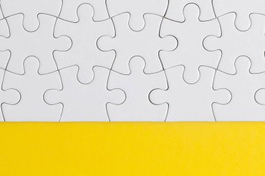 Sarı arka planda beyaz yapboz parçaları. İş solu