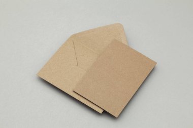 Gri arkaplanda boş kahverengi kraft kağıt ve zarf