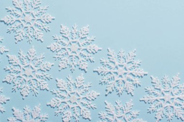 Pastel mavi zemin üzerine beyaz glitter kar tanesi kompozisyon