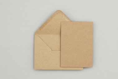 Gri arkaplanda boş kahverengi kraft kağıt ve zarf