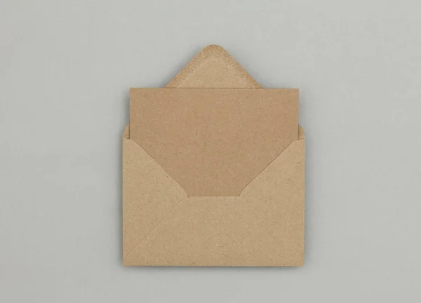 Pusta brązowa kartka papieru i koperta na szarym tle — Zdjęcie stockowe