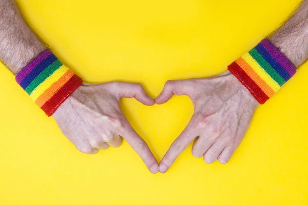 Srdce ruka s gay pýchou duha vlajka náramek na žluté bac — Stock fotografie