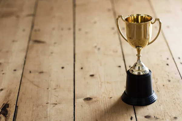 Prêmio troféu de vencedores de ouro em um fundo de madeira — Fotografia de Stock