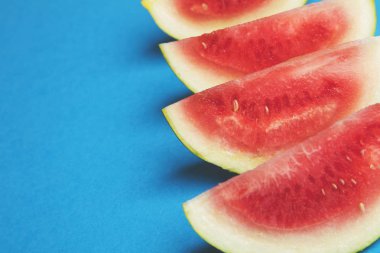 Parlak mavi arka planda taze dilimlenmiş karpuz.