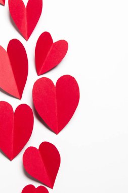 Beyaz arka planda kırmızı el yapımı kağıt kalpler.