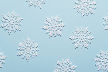 Pastel mavi zemin üzerine beyaz glitter kar tanesi kompozisyon