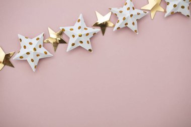 Pastel pembe üzerine beyaz ve altın yıldız süslemeleri. Mevsimlik fetiş