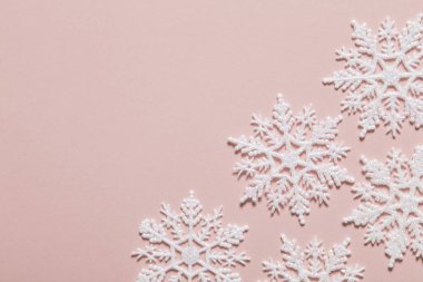 Pastel pembe arka planda beyaz simli kar tanesi kompozisyonu