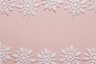Pastel pembe arka planda beyaz simli kar tanesi kompozisyonu