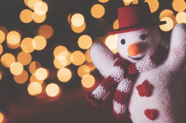 Bulanık bokeh perisine karşı şapkası ve atkısı olan neşeli kardan adam.