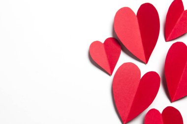 Beyaz arka planda kırmızı el yapımı kağıt kalpler.