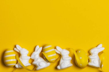 Parlak sarı arka planda Paskalya tavşanı ve yumurtalar