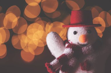 Bulanık bokeh perisine karşı şapkası ve atkısı olan neşeli kardan adam.