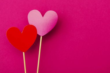 Kağıt kalpler parlak pembe bir arka plan üzerinde çubuk üzerinde