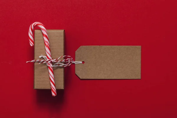 Cadeau de Noël festif avec canne à bonbons sur fond rouge — Photo