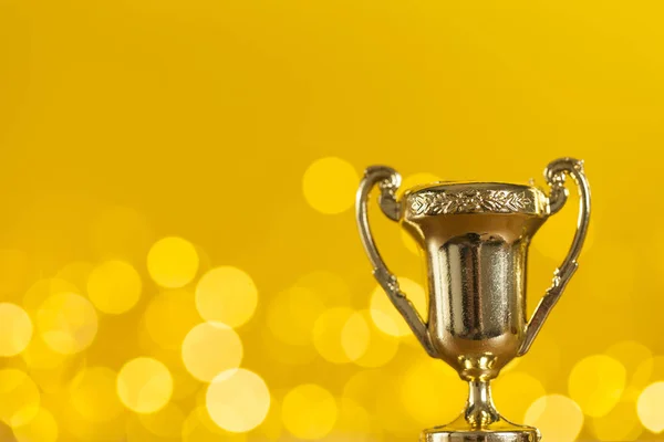 Troféu de prêmio de ouro contra fundo amarelo brilhante com borrado — Fotografia de Stock
