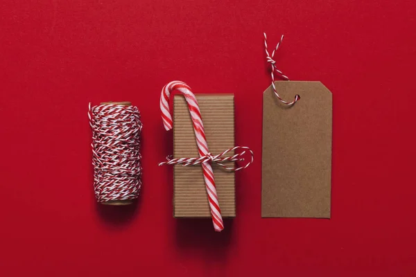 Slavnostní vánoční dárek s cukrovou třtinou na červeném pozadí — Stock fotografie