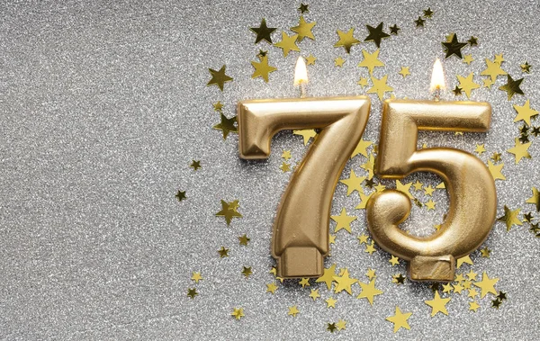 Number 75 gold celebration candle on star and glitter background — Stock Photo, Image