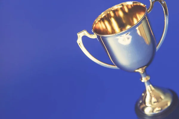 Taça de troféu de ouro vencedores em um fundo azul — Fotografia de Stock