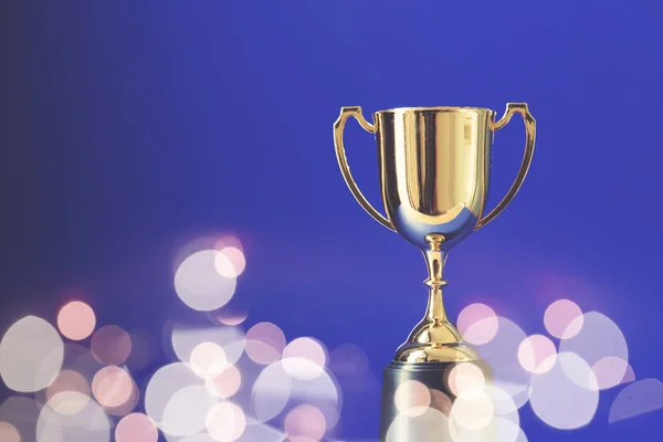 Gold winners trophy cup with bokeh blurred lights — Stock Photo, Image