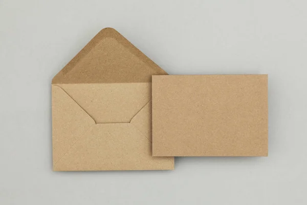 Порожня коричнева крафт-паперова картка та конверт на сірому фоні — стокове фото