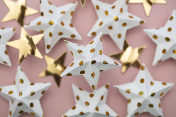 White and gold star decorations on a pastel pink. Seasonal festi