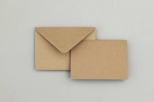 Prázdná hnědá kraft papírová karta a obálka na šedém pozadí — Stock fotografie