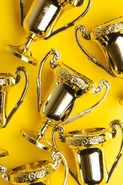 Zlatí vítězové úspěch trofej na žlutém pozadí — Stock fotografie