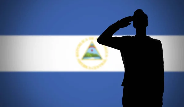 Silueta vojáka salutujícího proti vlajce Nikaragui — Stock fotografie