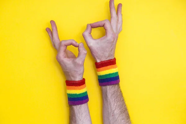 Okay hand gesture with gay pride rainbow flag wristband on a yel — Stock Photo, Image