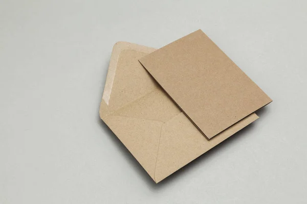 Tarjeta de papel kraft marrón en blanco y sobre sobre fondo gris —  Fotos de Stock