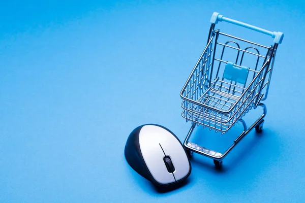 Shopping cart on a blue background with computer mouse