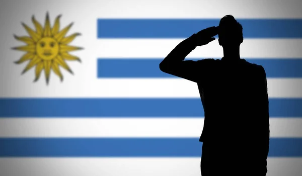 Sylwetka żołnierza salutującego przeciwko fladze urugwajskiej — Zdjęcie stockowe