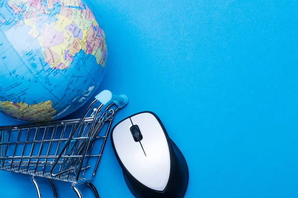 Mavi arka planda bilgisayar faresi ve küresi olan alışveriş arabası.