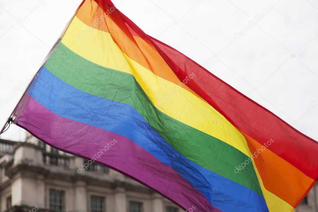 Gay rainbow flag being waved at an LGBT gay pride march in Londo