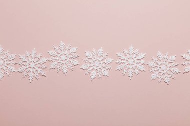 Pastel pembe arka planda beyaz simli kar tanesi kompozisyonu