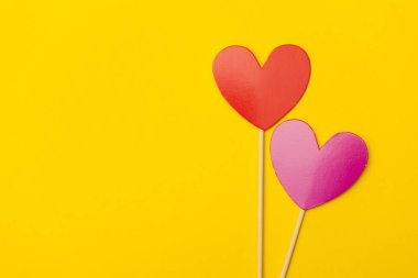 Parlak sarı bir zemin üzerinde bir çubuğun üzerinde kağıt kalp