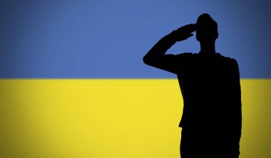 Ukrayna bayrağına selam veren bir askerin silueti.