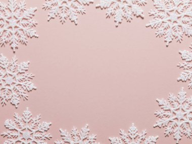 Pastel pembe arka planda beyaz simli kar tanesi kompozisyonu