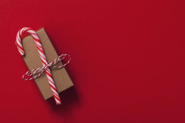 Kırmızı arka planda şeker kamışı ile Noel hediyesi