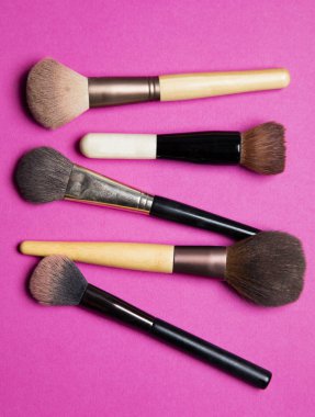 Pembe arka planda makyaj makyaj malzemesi fırçaları