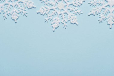 Pastel mavi zemin üzerine beyaz glitter kar tanesi kompozisyon