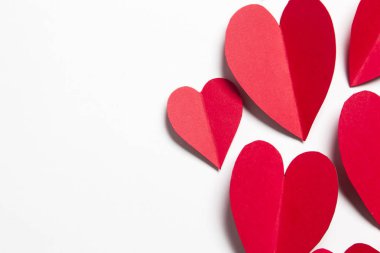 Beyaz arka planda kırmızı el yapımı kağıt kalpler.