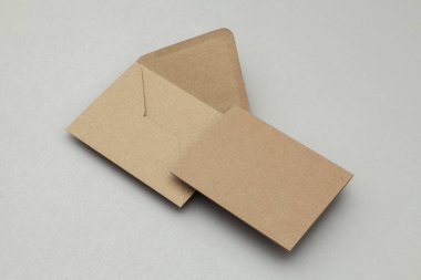 Gri arkaplanda boş kahverengi kraft kağıt ve zarf