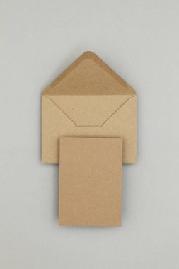 Gri arkaplanda boş kahverengi kraft kağıt ve zarf