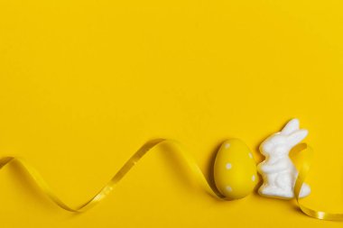 Parlak sarı arka planda Paskalya tavşanı ve yumurtalar