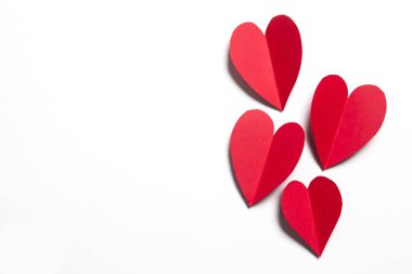 Beyaz arka planda kırmızı el yapımı kağıt kalpler.